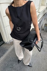 Must räbalaheline särk ümmarguse kaelusega, kombineeritud heleda beeži pükstega, hoides lühikeste rihmadega musta nahkkotti. Hõbedane ümmargune kaelakee.