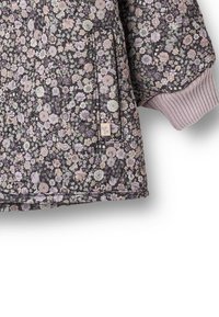 Gėlėtu raštu siuvinėtas striukė su tamsia fono spalva, violetinių tonų gėlėmis, gofruotais rankogaliais ir šonine kišene su prekės ženklo žyme.