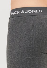Graue Stretch-Baumwoll-Boxershorts mit einem schwarzen Bund, auf dem "JACK & JONES" in weißem Text steht. Glatte Textur und enganliegendes Design.