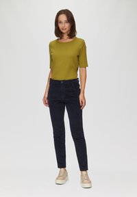 Groen geribbeld T-shirt met korte mouwen, gecombineerd met navy corduroy slim-fit broek en beige platform sneakers. Effen kleuren en slank ontwerp.