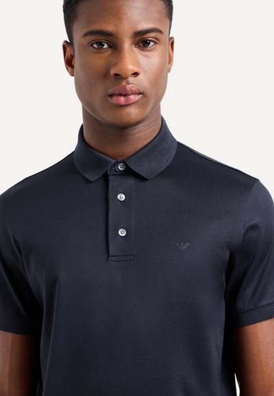 Polo shirt blu navy realizzato in tessuto texturizzato, con colletto classico, pattina con tre bottoni e piccolo logo sul petto.