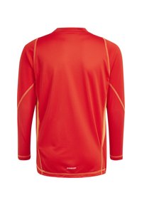 Rode sportshirt met lange mouwen en een gestructureerde afwerking, met lichtoranje accenten langs de naden en het "AEROREADY" logo dichtbij de zoom.