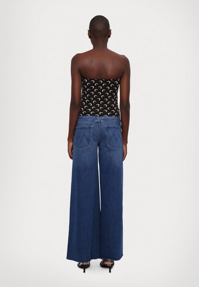 Top noir sans bretelles avec un motif de croissant de lune associé à un jean en denim bleu à jambes larges. Tissu lisse et coupe ample.