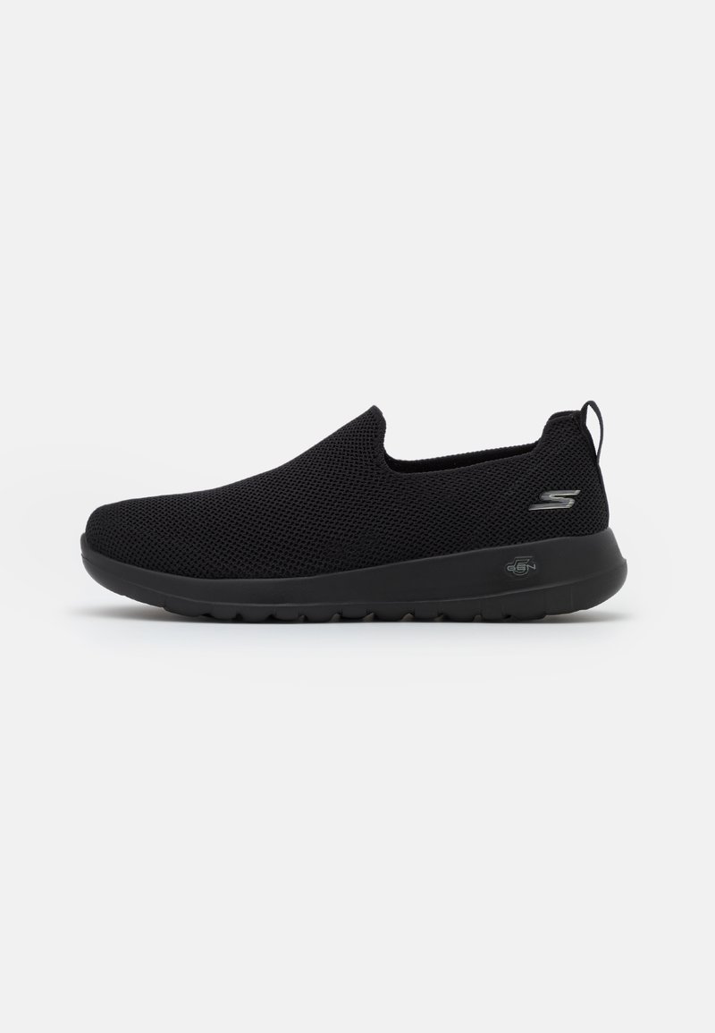 Baskets slip-on noires en mesh avec semelle coussinée, profil bas et petit logo près du talon sur fond blanc.