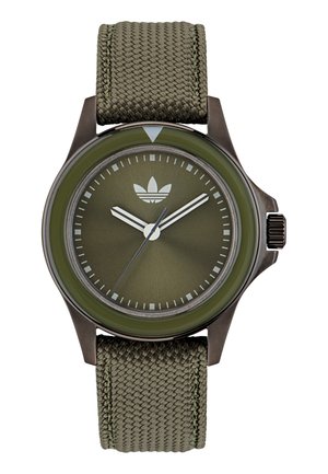 Montre vert olive avec un boîtier en métal, un bracelet texturé, un cadran minimaliste, des index horaires argentés et un mouvement à trois aiguilles.