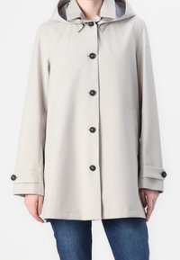 Impermeable gris claro con capucha, que presenta botones negros, dos bolsillos frontales y una tela suave y resistente al agua.