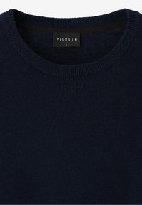 Mörkblå stickad tröja med rund halsringning. Tyget har ett strukturerat mönster och ett märke med texten "VISTULA" i vitt.