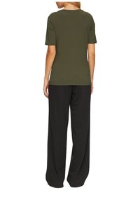 Olijfgroen T-shirt met korte mouwen, ronde halslijn en een gladde textuur, gecombineerd met zwarte wijde broek.