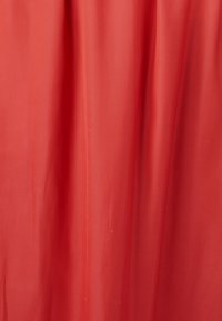 Tela roja con una textura suave y ligera, dispuesta de manera delicada, mostrando pliegues sutiles y un color sólido sin patrones ni herrajes.