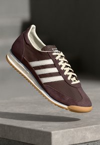 Sneaker in suede bordeaux con strisce bianche, pannello laterale in rete testurizzata, suola in gomma naturale e dettagli crema su linguetta e lacci.