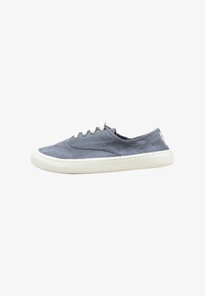 Lage casual slip-on sneaker van vervaagd blauw canvas met witte veters en dikke witte rubberen zool, gezien vanaf de zijkant.