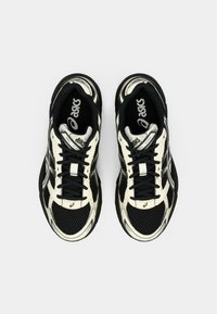 Musthave mustvalged mustristsid, millel on võrgust ülemine osa, paelad ja ainulaadne laineline disain. Tallal on tekstuuriga muster ja peegeldavad detailid.