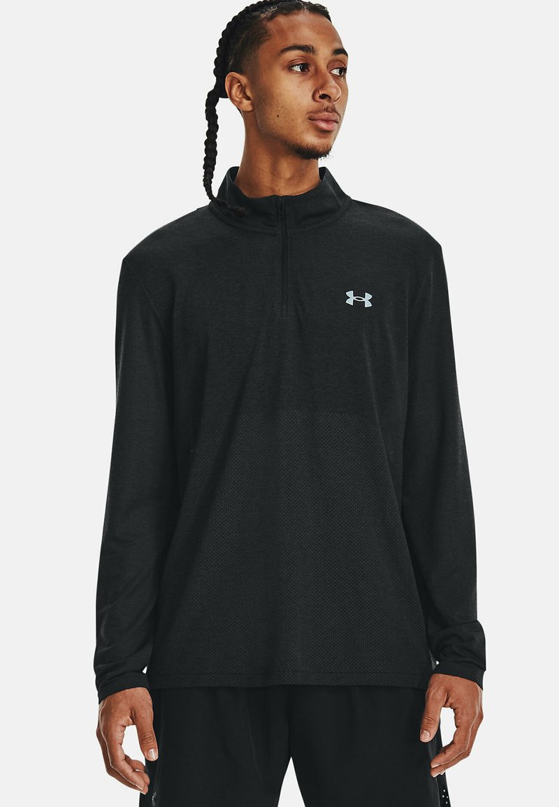 Sort langærmet trøje med halvdelslynlås og svedtransporterende stof, struktureret mønster og grå Under Armour-logo på brystet.