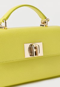 Μικρή lime πράσινη υφασμάτινη τσάντα χειρός με κοντή λαβή και ορθογώνιο χρυσό μεταλλικό κλείσιμο σε λευκό φόντο.