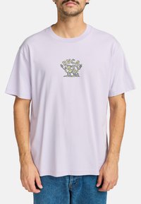 Camiseta de algodón color púrpura claro con mangas cortas, que presenta un colorido diseño gráfico bordado en el pecho con texto y patrones.