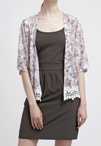 Blumenmuster-Kimono in sanften Rosa- und Grautönen mit Spitzenbesatz, getragen über einem dunklen, enganliegenden Kleid. Leichter, fließender Stoff.