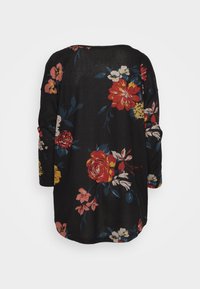 Svart blommig blus med stora röda, rosa och gula blommor, långa ärmar och rundad nederkant. Mjuk tyg med avslappnad passform.