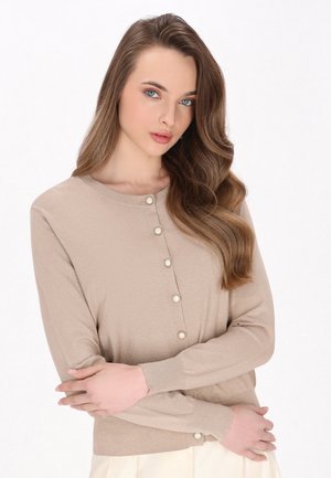 Béžový cardigan vyrobený z třpytivé pleteniny, s kulatým výstřihem a perlami podobnými knoflíky vpředu. Dlouhé rukávy a přiléhavý střih.