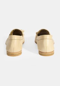 Beige Lederloafers mit glatter Textur, niedrigem Absatz und subtilen Nähdetails. Helle Gummi-Sohlen runden das Design ab.