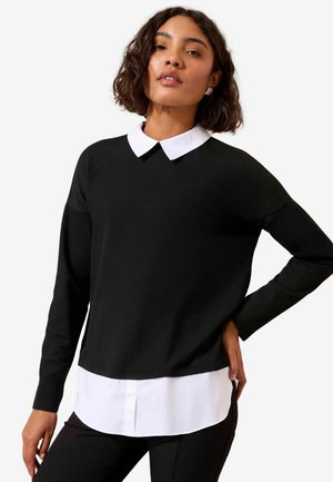 Black sweater with a white collar, long sleeves, and a relaxed fit, layered over a white shirt. Smooth texture, simple design.