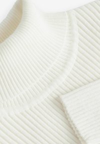 Sweter prążkowany w kremowym kolorze z wysokim, okrągłym dekoltem. Miękka tekstura z poziomymi paskami. Posiada dopasowane zakończenie rękawów.