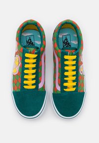 Baskets colorées avec un bout et un talon en suède vert, un motif à carreaux vibrant en rouge et vert, des lacets jaunes et des accents latéraux roses.