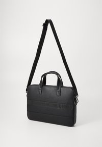 Black textured briefcase with dual handles, adjustable shoulder strap, and a horizontal strip accent. Features a zip closure.