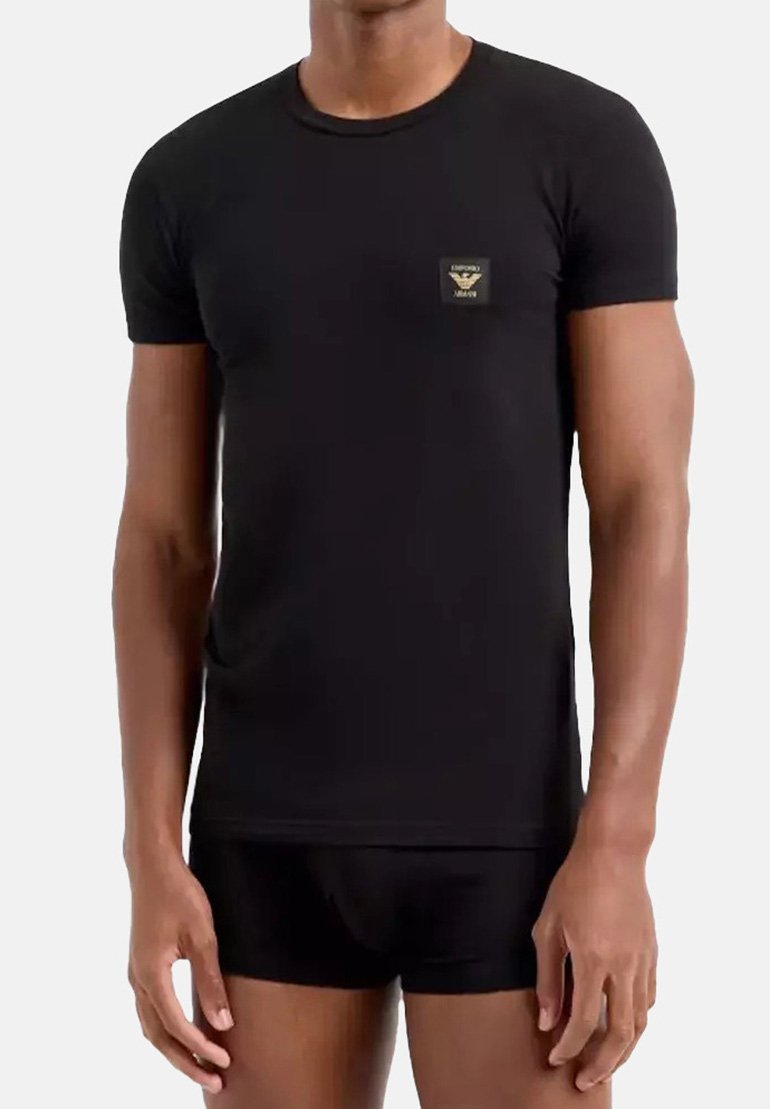 T-shirt nera a maniche corte realizzata in un tessuto morbido, con una piccola toppa logo quadrata sul lato sinistro del petto. Design aderente.