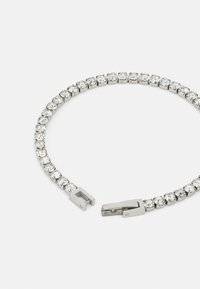 Silver-tone bracelet featuring rounded links set with clear, sparkling rhinestones. Secure clasp closure; smooth, glossy finish.