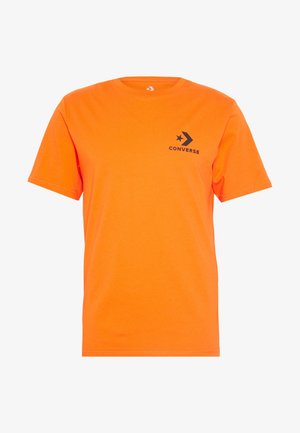 T-shirt à manches courtes en coton orange vif. Présente un logo "Converse" noir avec un motif étoile et flèche sur la poitrine.