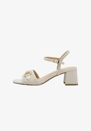 Sandalia blanca de tacón con parte superior trenzada, correa ajustable en el tobillo y detalle en tono dorado. Tacón cuadrado y suela lisa para mayor estabilidad.