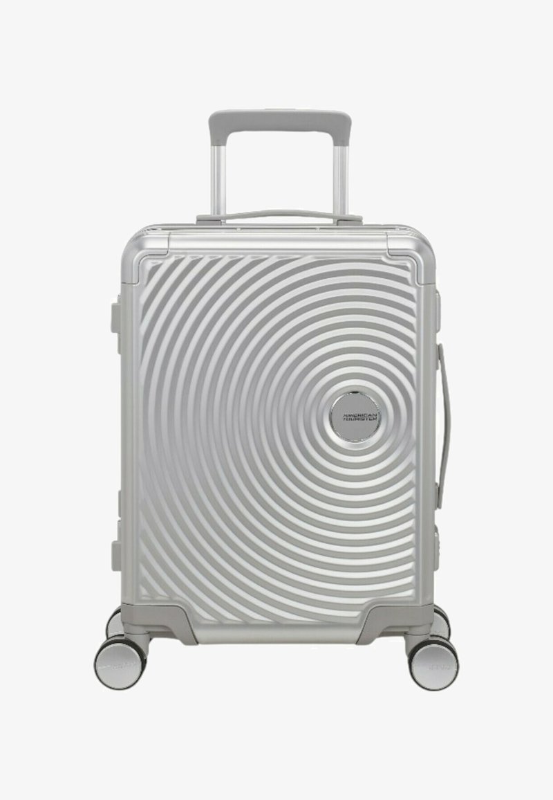 Valigia argentata con superficie a texture a spirale, esterno rigido, manico estensibile e quattro ruote per la mobilità.