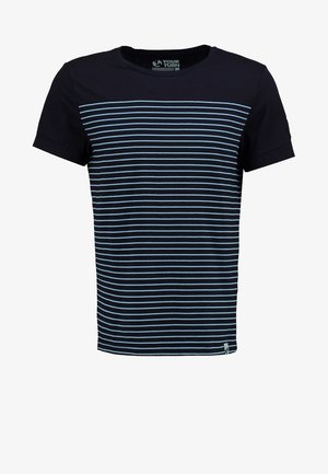 Homme portant un t-shirt rayé bleu marine et blanc, un short cargo noir et des baskets noires, marchant sur un fond blanc.