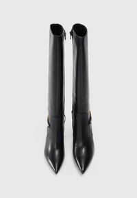Knee-high black leather boots with a pointed toe, side zippers, and decorative hardware accent on the lower section. Smooth texture.