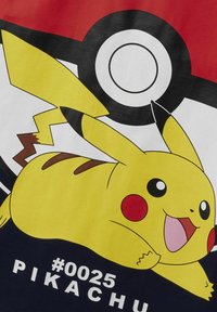Sárga Pikachu figura piros pofákkal, egy fekete-fehér Poké Ball dizájnnal díszített pólón ábrázolva. Az alatta lévő szöveg: "#0025 PIKACHU."