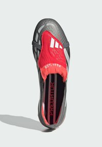 Sort og rød fodboldsko med en tekstureret overdel, reflekterende sølvdetaljer, behagelig pasform og fremtrædende "PREDATOR" branding indvendigt.