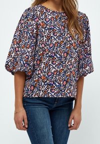 Top con stampa floreale e maniche a sbuffo. Presenta motivi vibranti in rosa, blu e arancione su uno sfondo chiaro. Realizzato in tessuto morbido e leggero.