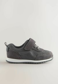 Grå sneaker med tyg- och mockamaterial, kardborreband, snördetalj, låg profil, vit mellansula och strukturerad gummisula.