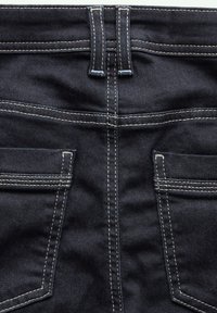 Jeans de mezclilla oscura con costuras blancas en contraste, dos bolsillos traseros y un diseño de cintura alta con lazos para cinturón.