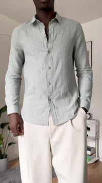 Light green linen button-up shirt with a collar, long sleeves, and a straight hem, paired with cream-colored trousers.
