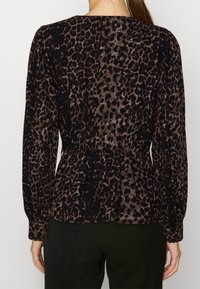Černý top s dlouhým rukávem a leopardím vzorem, s nabíraným pasem a texturovanou tkaninou. Má kulatý výstřih a přiléhavé rukávy.