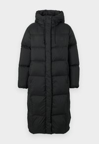 Casaco puffer preto longo, acolchoado, com capuz, cordões, botões de pressão e fechos laterais de pressão, projetado para aquecer e proteger contra as intempéries.