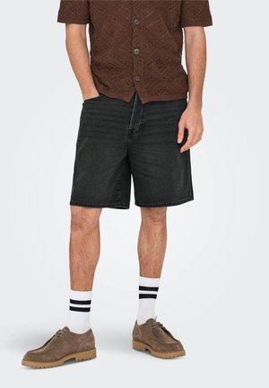 Black denim shorts with a relaxed fit, paired with brown textured short-sleeve shirt, white socks with black stripes, and brown shoes.