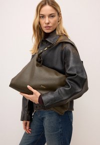 Olívazöld bőr táska laza kialakítással és texturált felülettel, hosszú pánttal és aranyszínű kiegészítőkkel.