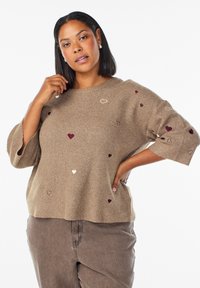 Maglione lavorato a maglia in beige con una vestibilità ampia e maniche 3/4. Presenta cuori ricamati sparsi in bordeaux e crema. Texture morbida.