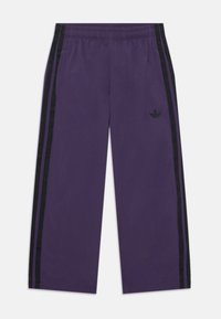 Pantalones deportivos morados con franjas laterales negras, cintura elástica y logotipo bordado. El material parece suave con una textura lisa.