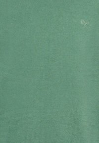 T-shirt en tricot à manches courtes de couleur verte unie. Texture lisse avec un fin côtelage. Présente un petit logo brodé dans le coin supérieur droit.