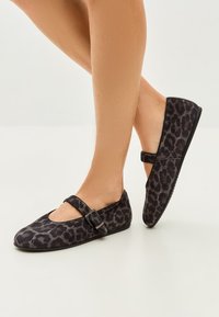 Leopard print flat shoes with a rounded toe and buckle strap, made of soft fabric, featuring a low-profile black sole.