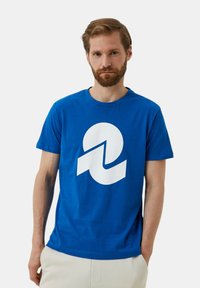 T-shirt in cotone blu con un grande design grafico bianco che assomiglia al numero due. Maniche corte e scollatura a girocollo.