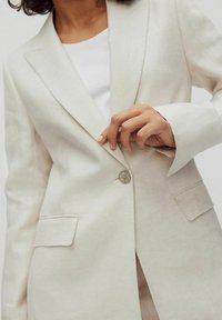 Lichtbeige linnen blazer met een enkele knoopsluiting, notch-lapels en twee voorzakken. Soepele textuur en een licht gestructureerde pasvorm.